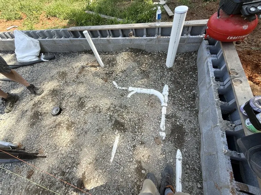 Ground rough-in drain piping inside a block foundation before the floor is poured